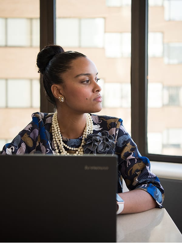 Woman in front of laptop gazing into distance